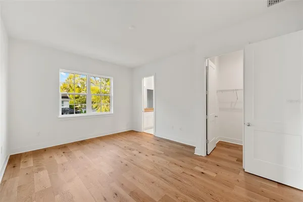 an empty room with wooden floor and window