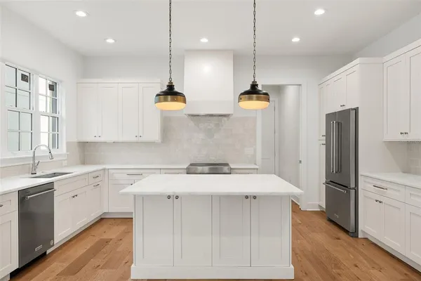 a kitchen with stainless steel appliances kitchen island a refrigerator sink and cabinets