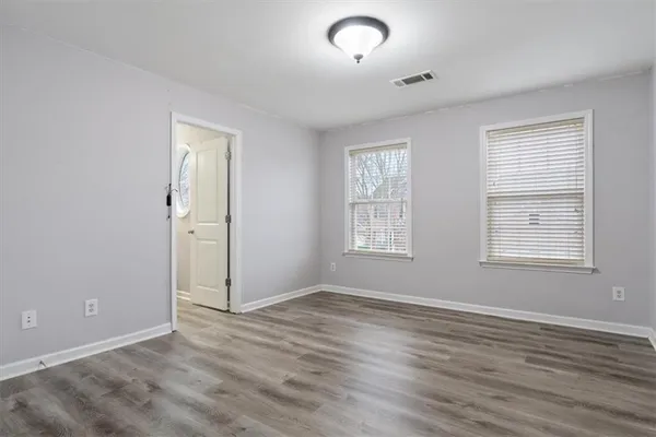 an empty room with wooden floor and windows