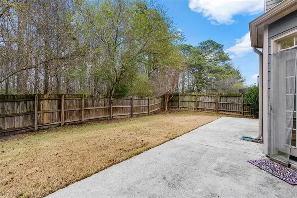 a view of backyard with wooden fence and large trees