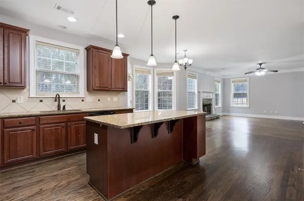 a kitchen with stainless steel appliances granite countertop a sink a stove and a wooden floor