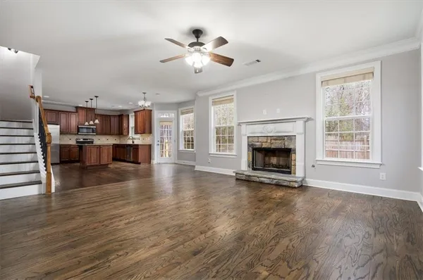 an empty room with wooden floor a ceiling fan and windows