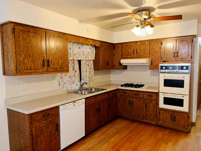 an empty room with wooden floor cabinet and windows