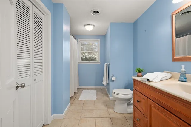 a bathroom with a granite countertop sink a toilet a mirror and shower