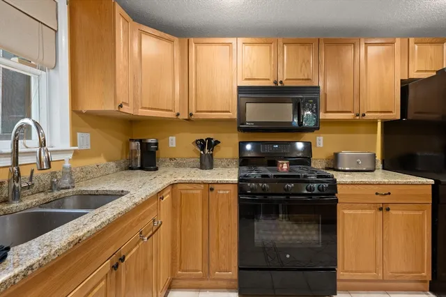 a kitchen with granite countertop a stove top oven microwave and cabinets