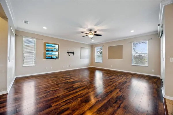 a view of an empty room with wooden floor and a window