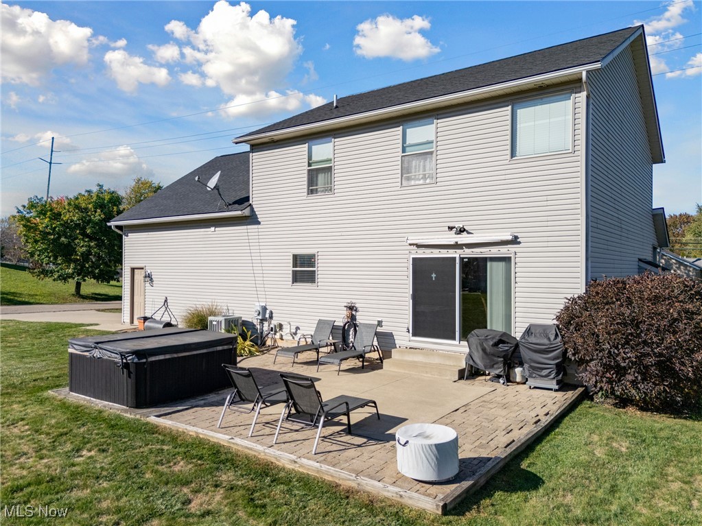 3048 Wright Road Northwest Uniontown, OH 44685 - Photo 6 of 30 Back of property with a yard, a patio area, a hot tub, and a shingled roof
