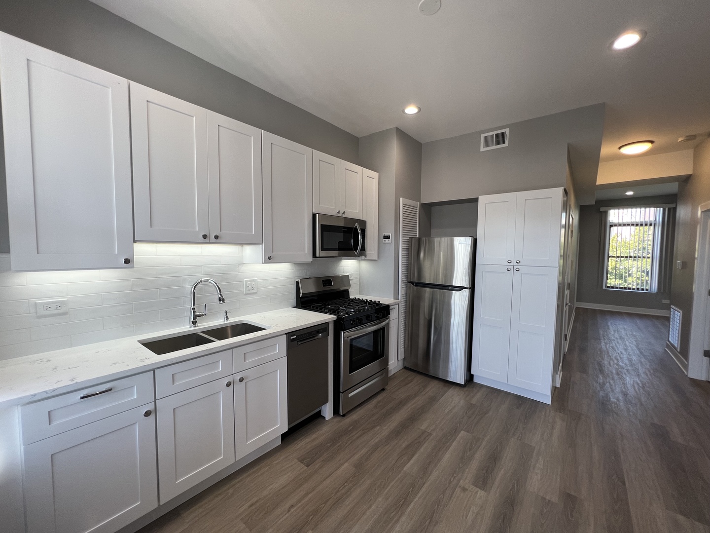 1227 West Ohio Street, Unit 3 Chicago, IL 60642 - Photo 2 of 18 a kitchen with a sink wooden floor and stainless steel appliances