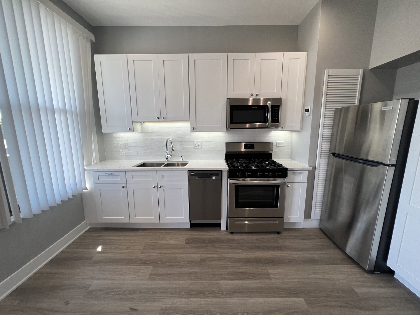 1227 West Ohio Street, Unit 3 Chicago, IL 60642 - Photo 3 of 18 a kitchen with a refrigerator stove and white cabinets