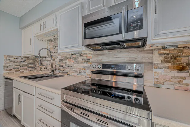 a kitchen with granite countertop a stove and white cabinets