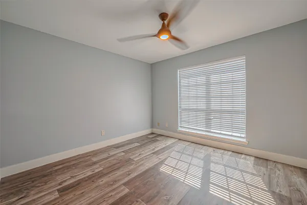 a view of an empty room with a window and wooden floor