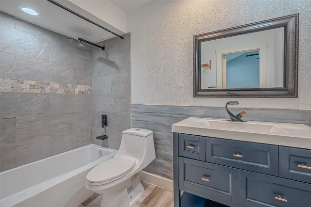a bathroom with a granite countertop toilet a sink and a bathtub