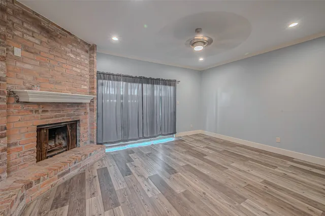 a view of an empty room with wooden floor and a fireplace