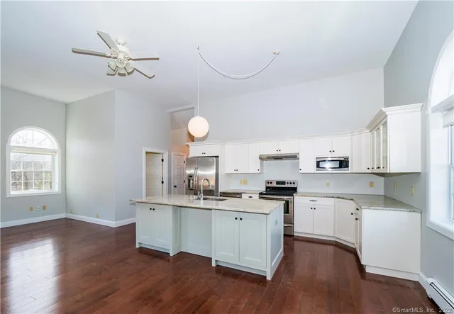 a kitchen with a stove a sink and white cabinets with wooden floor