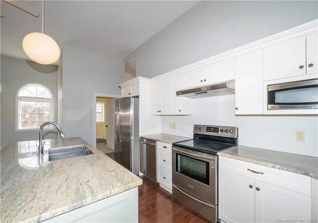 a kitchen with granite countertop a sink stainless steel appliances and cabinets