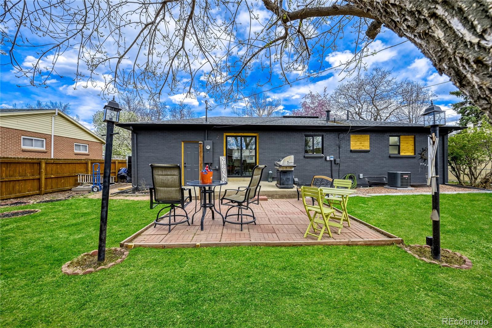 6623 Kipling Street Arvada, CO 80004 - Photo 35 of 39 a view of a backyard with table and chairs potted plants and a large tree