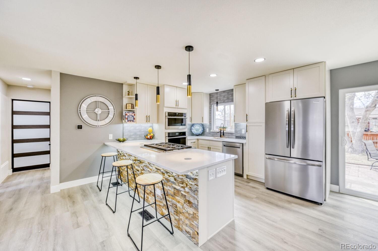 6623 Kipling Street Arvada, CO 80004 - Photo 4 of 39 a kitchen with stainless steel appliances a refrigerator a stove a sink a dining table and chairs with wooden floor
