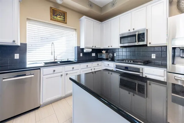 a kitchen with granite countertop white cabinets and white appliances