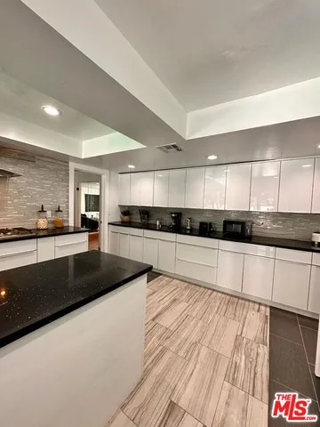 a large kitchen with stainless steel appliances granite countertop a large counter top and a stove top oven