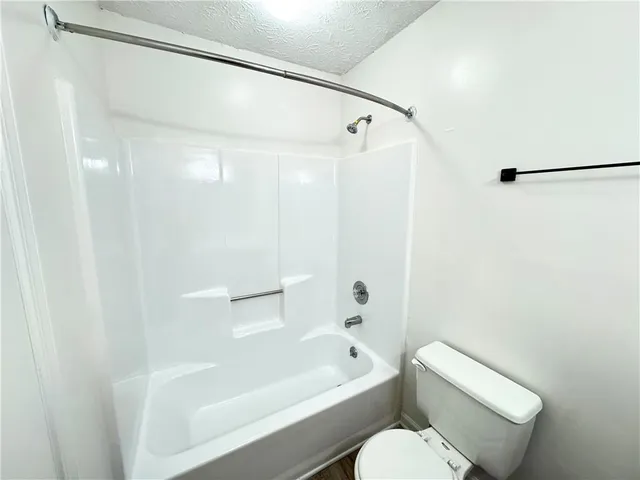 a white toilet sitting next to a bath tub and a shower