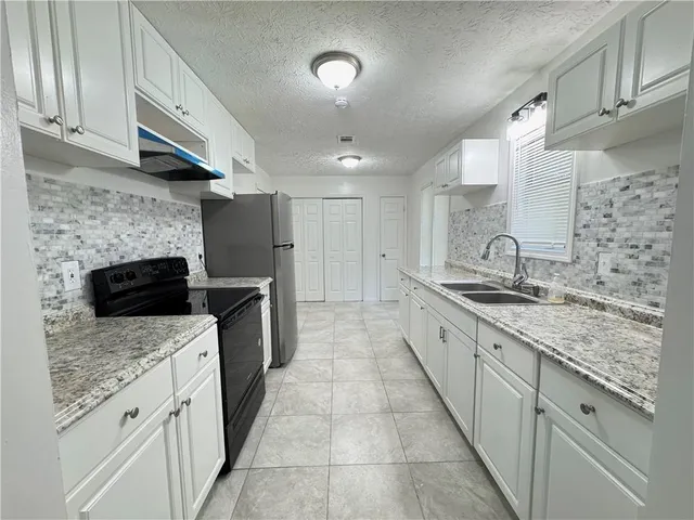 a large kitchen with a granite countertop double vanity sink and a stove