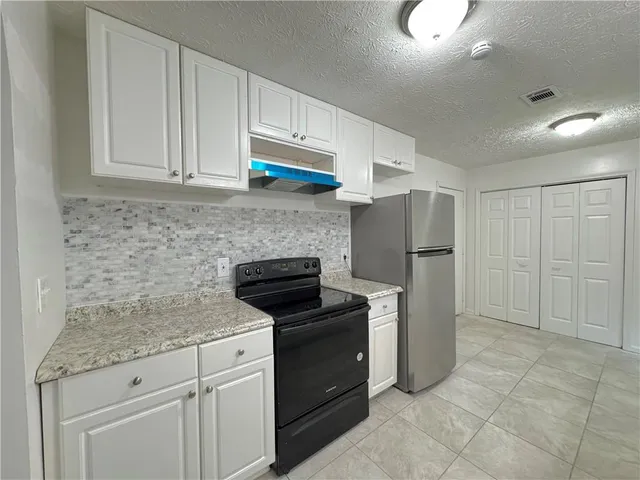 a kitchen with granite countertop a refrigerator stove and cabinets
