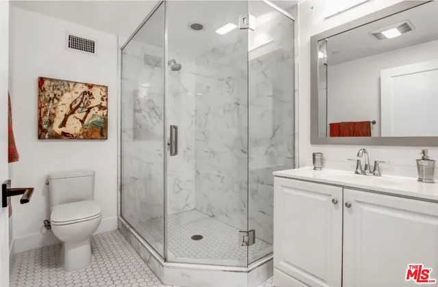 a bathroom with a toilet sink vanity granite and shower