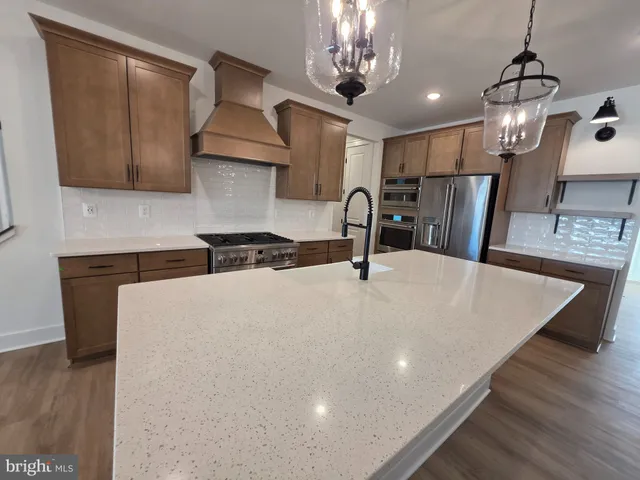 a kitchen with stainless steel appliances granite countertop a sink a stove and a wooden floors
