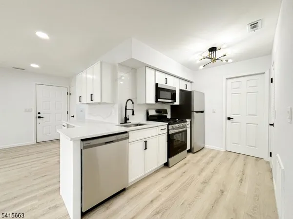 a kitchen with kitchen island a sink stainless steel appliances and cabinets