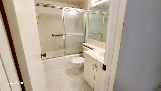 a bathroom with a granite countertop shower and a toilet