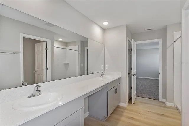 a spacious bathroom with a double vanity sink mirror and shower