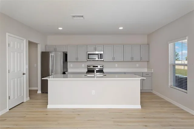 a view of kitchen with stainless steel appliances granite countertop a stove a sink and a refrigerator