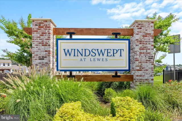 a sign that is sitting on a brick wall with a building in the background