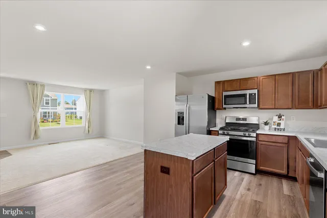 a kitchen with stainless steel appliances granite countertop a stove top oven a sink dishwasher and a refrigerator with wooden floor