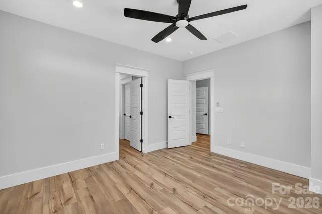 an empty room with wooden floor and ceiling fan