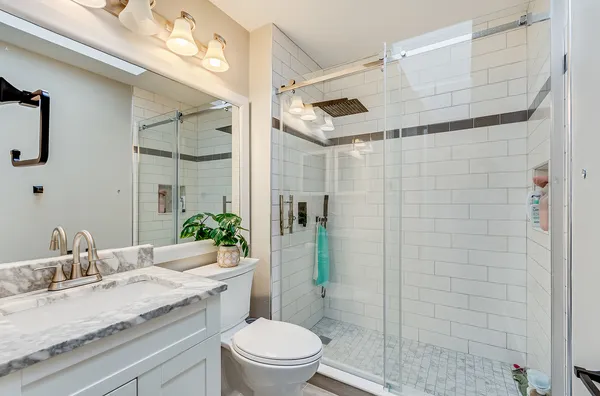 a bathroom with a granite countertop sink a toilet a mirror and shower