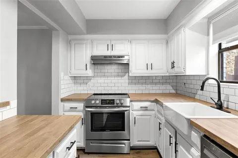 a kitchen with granite countertop a stove sink and cabinets