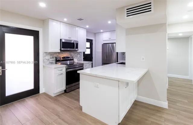 a kitchen with a refrigerator a stove top oven a sink and dishwasher with wooden floor