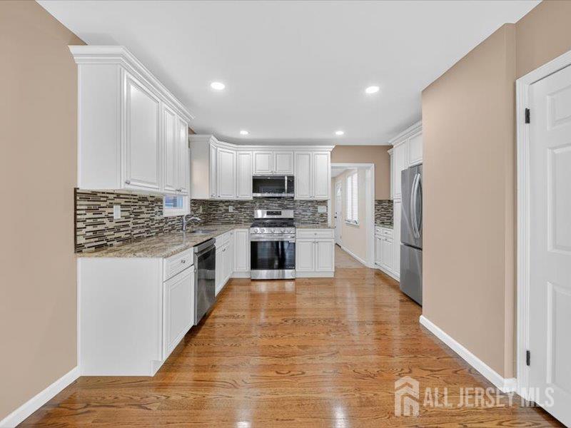 54 Freeman Street Woodbridge, NJ 07095 - Photo 14 of 35 a kitchen with granite countertop a stove top oven a sink and cabinets