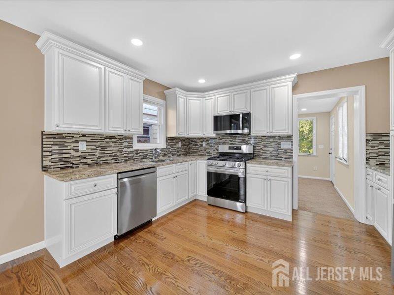 54 Freeman Street Woodbridge, NJ 07095 - Photo 16 of 35 a kitchen with granite countertop a stove top oven a sink dishwasher and a refrigerator with wooden floor