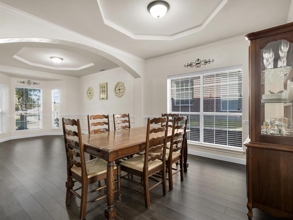 1803 Timber Ridge Drive Frisco, TX 75036 - Photo 12 of 40 Dining area with a tray ceiling, arched walkways, dark wood finished floors, and crown molding