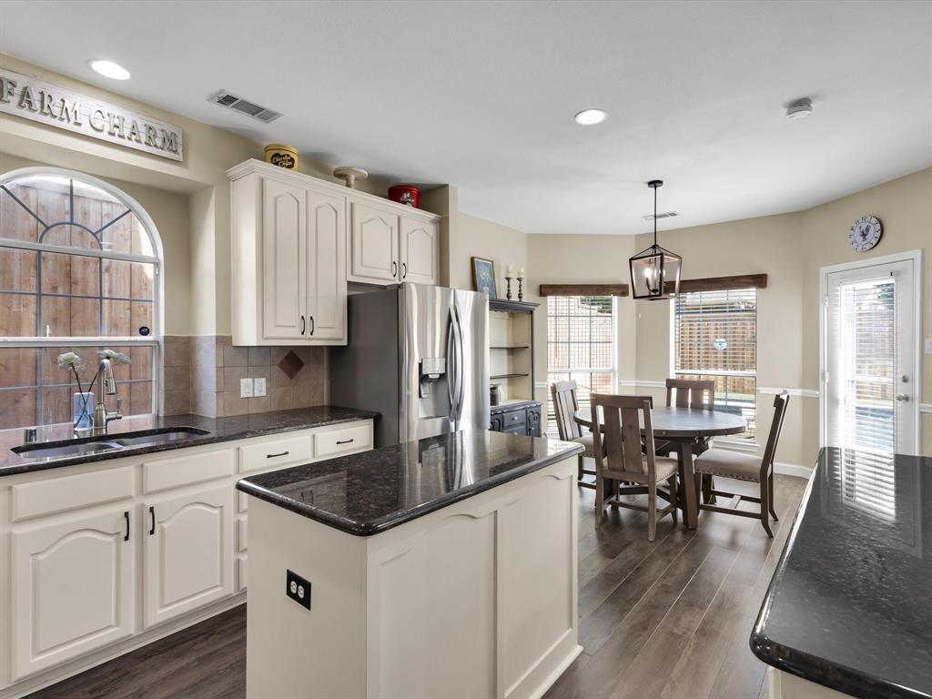 1803 Timber Ridge Drive Frisco, TX 75036 - Photo 17 of 40 Kitchen featuring dark stone counters, tasteful backsplash, decorative light fixtures, stainless steel fridge, and a kitchen island