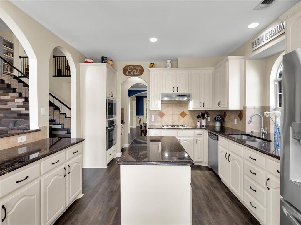 1803 Timber Ridge Drive Frisco, TX 75036 - Photo 18 of 40 Kitchen with arched walkways, dark stone countertops, a kitchen island, dark wood-style flooring, and recessed lighting