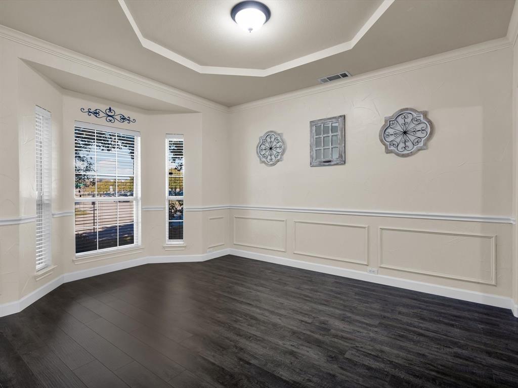 1803 Timber Ridge Drive Frisco, TX 75036 - Photo 9 of 40 Spare room with dark wood-type flooring, a wainscoted wall, a decorative wall, a tray ceiling, and crown molding