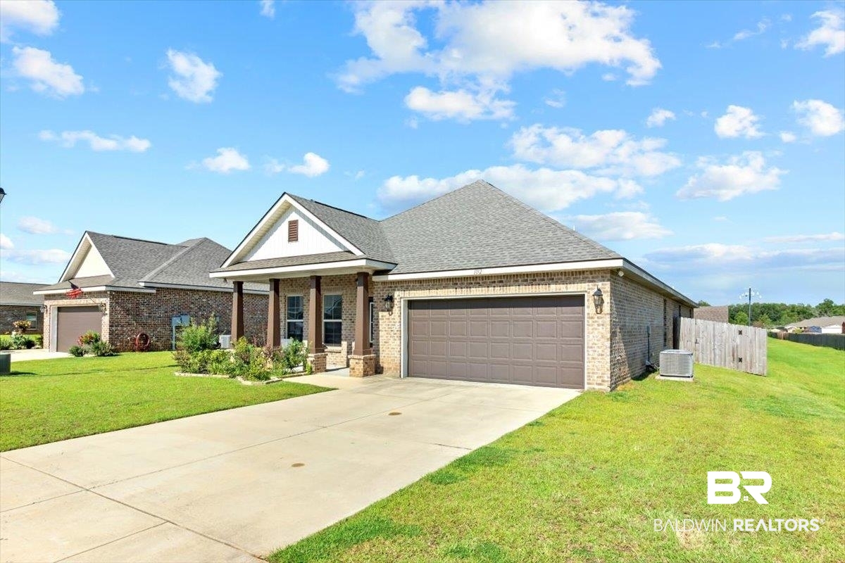 1112 Stella Road Foley, AL 36535 - Photo 2 of 33 View of front of house featuring a garage, a front lawn, brick siding, a shingled roof, and driveway