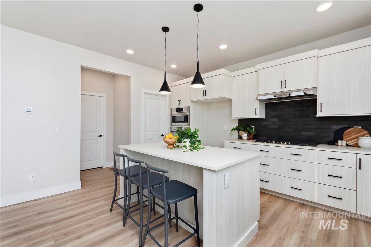 2702 West Gidran Meridian, ID 83642 - Photo 10 of 30 Kitchen with a breakfast bar area, hanging light fixtures, tasteful backsplash, light wood-type flooring, and recessed lighting