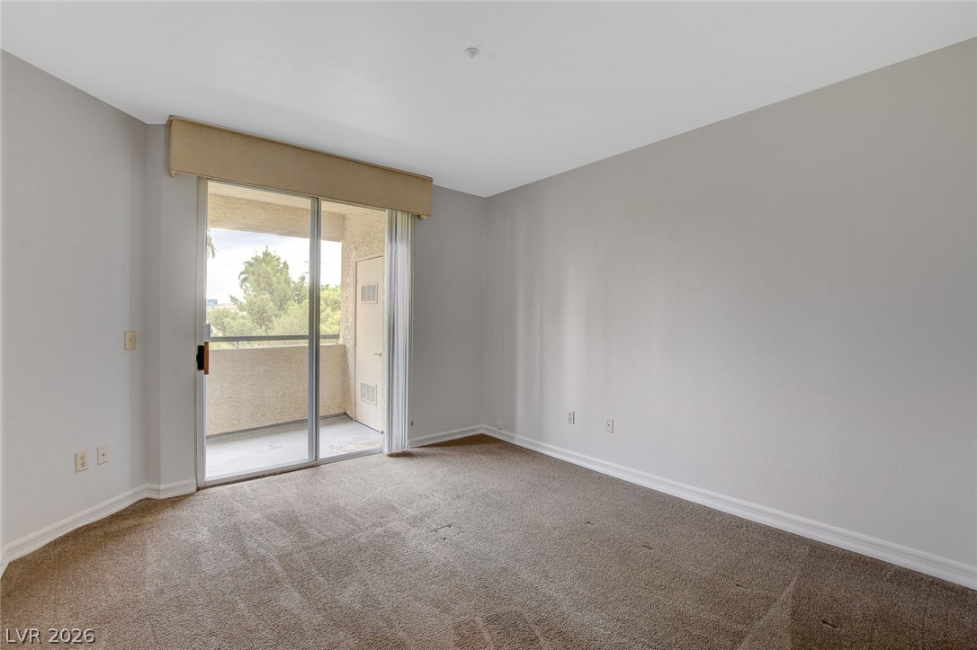 230 East Flamingo Road, Unit 404 Las Vegas, NV 89169 - Photo 20 of 34 Sliding glass doors open from the carpeted bedroom onto a private balcony.