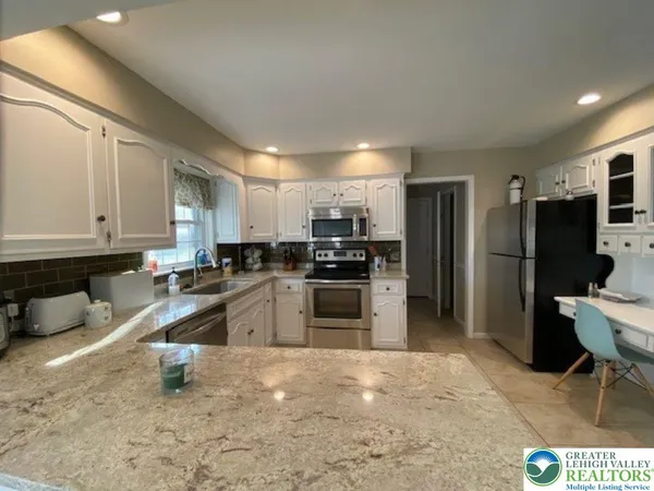 a kitchen with stainless steel appliances kitchen island granite countertop a refrigerator stove and sink