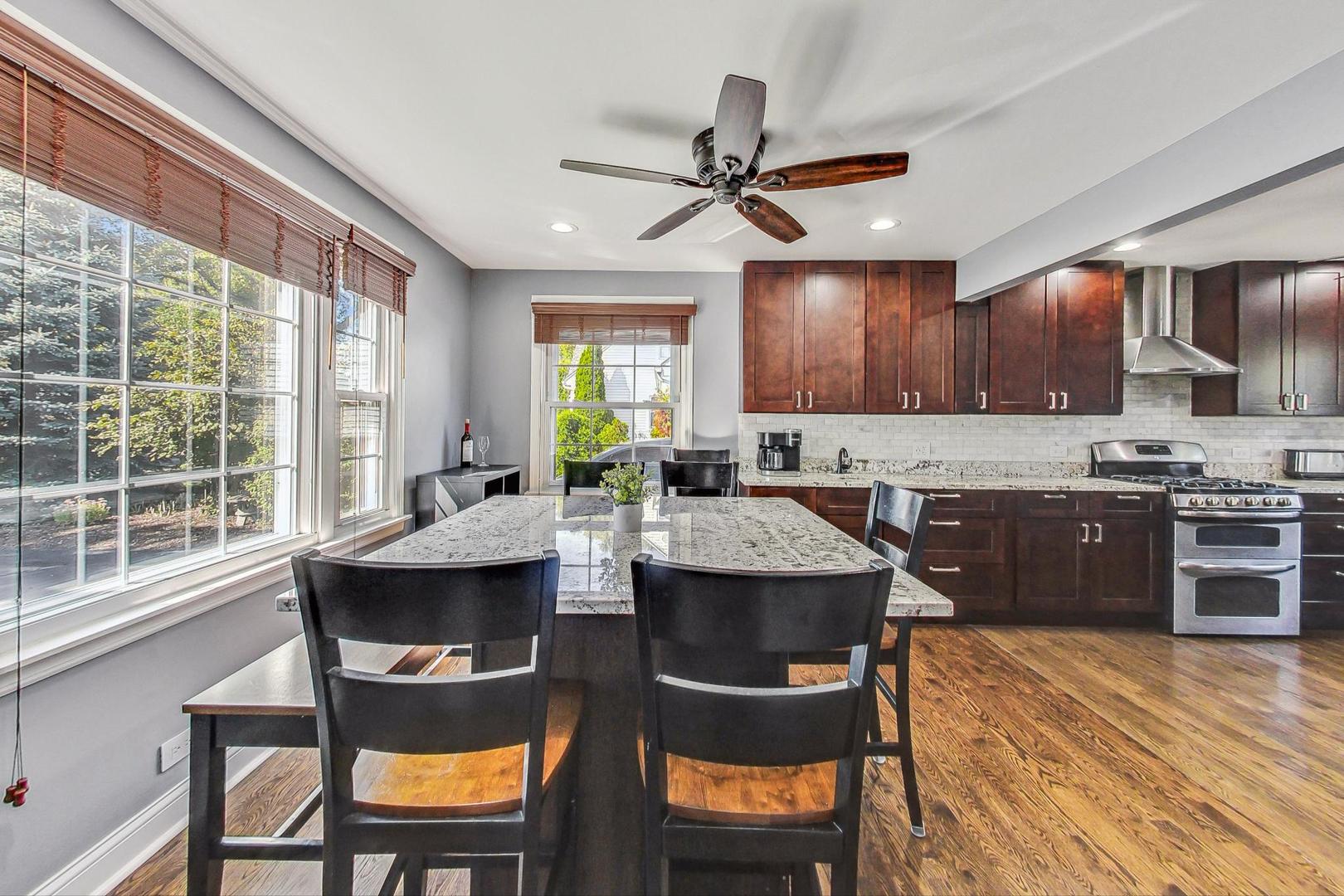 1738 Morse Avenue Des Plaines, IL 60018 - Photo 5 of 31 a kitchen with stainless steel appliances granite countertop a stove a refrigerator a sink a dining table and chairs with wooden floor