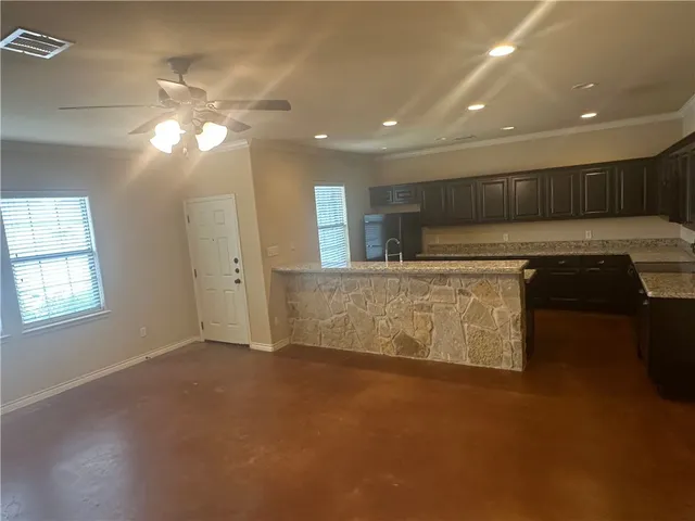 a view of kitchen with kitchen island stainless steel appliances a sink cabinets and living room view